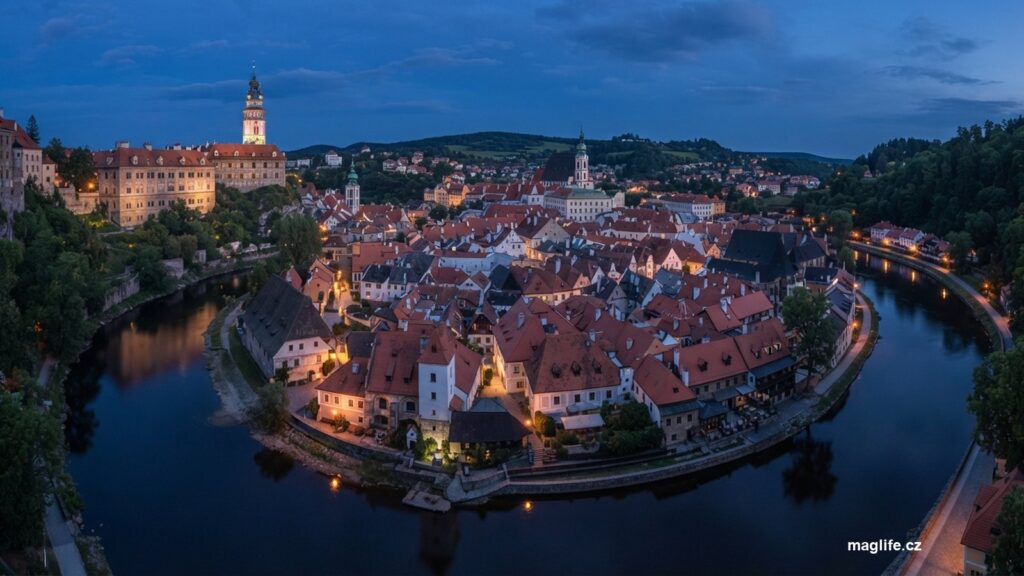 Historické město v ohybu řeky za soumraku se zámeckou věží nad ním