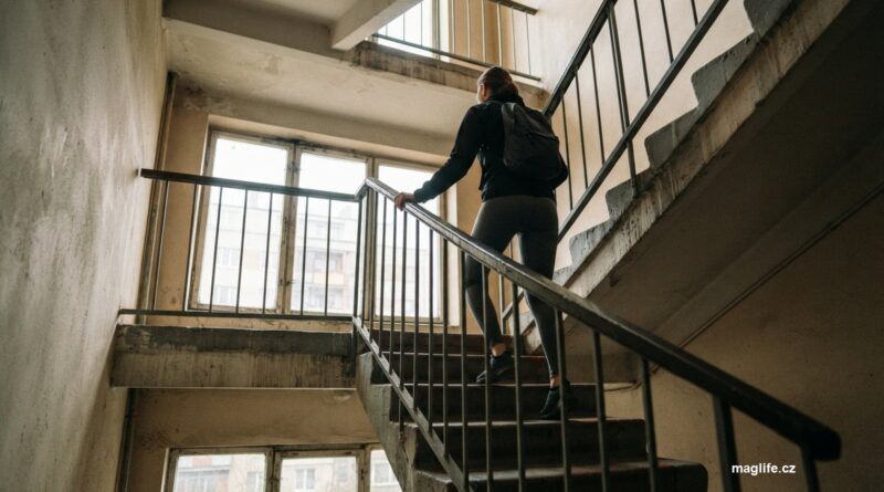Člověk ve sportovním oblečení stoupá po betonovém schodišti činžovního domu