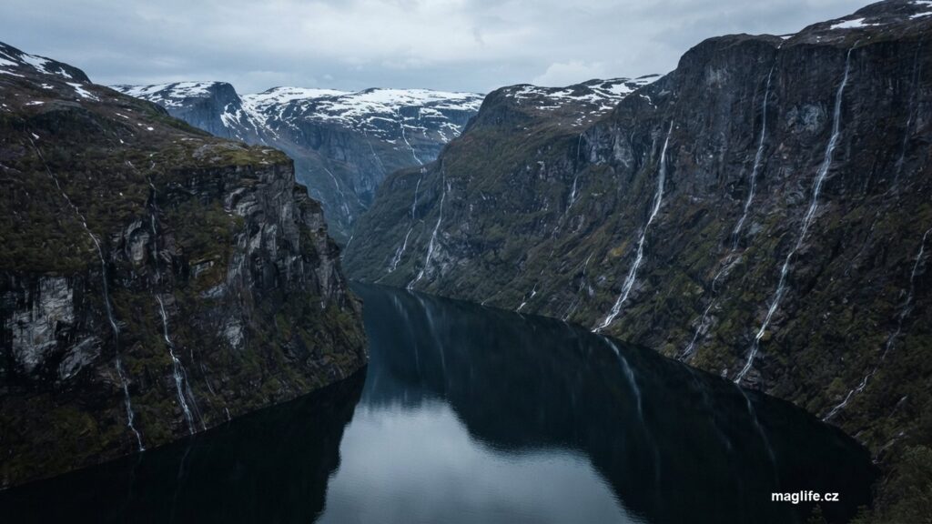 Úzký fjord se svislými stěnami, vodopády a sněhem na náhorní plošině